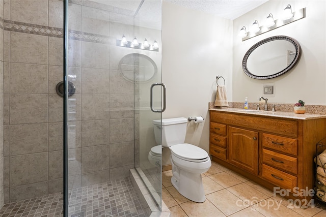 bathroom featuring a textured ceiling, vanity, walk in shower, tile patterned flooring, and toilet