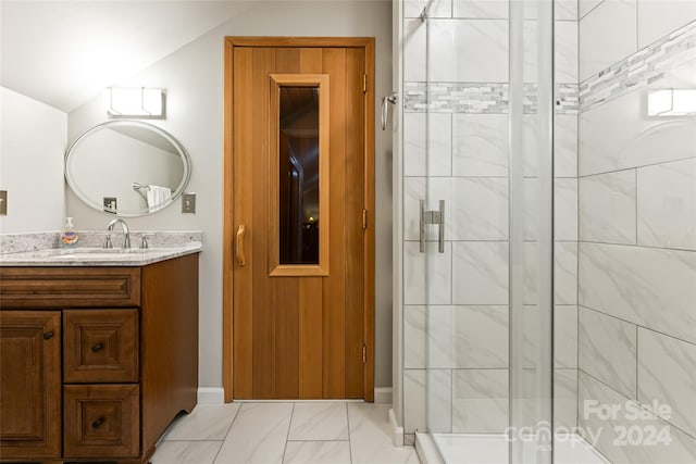 bathroom with a shower with door, vanity, vaulted ceiling, and tile patterned flooring