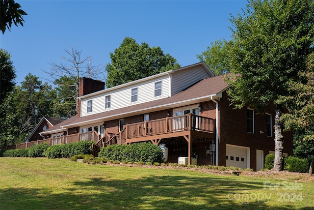 back of property featuring a wooden deck, a garage, and a lawn