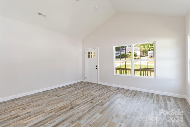 unfurnished room with high vaulted ceiling and light hardwood / wood-style flooring