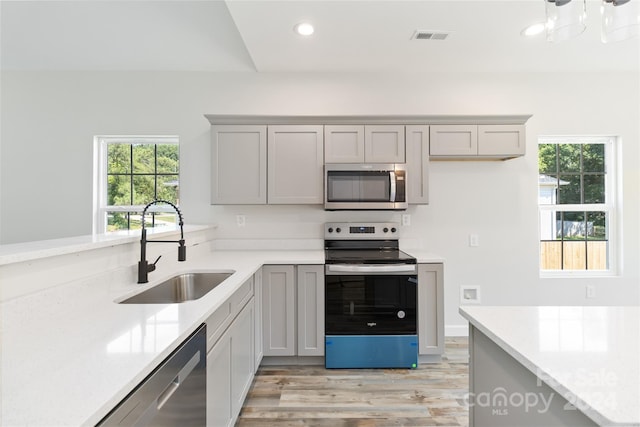 kitchen featuring light stone countertops, sink, appliances with stainless steel finishes, and gray cabinetry