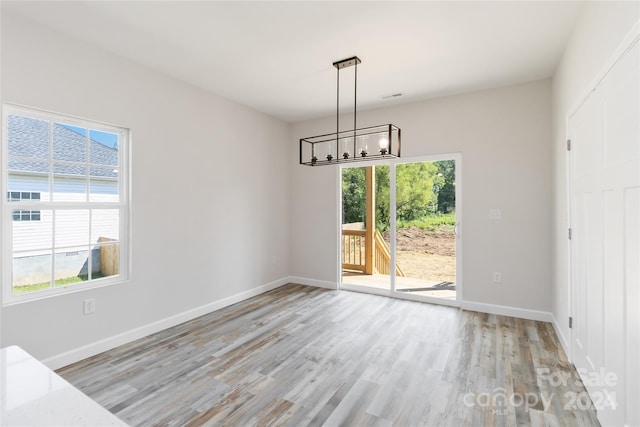 unfurnished dining area featuring a chandelier and light hardwood / wood-style floors