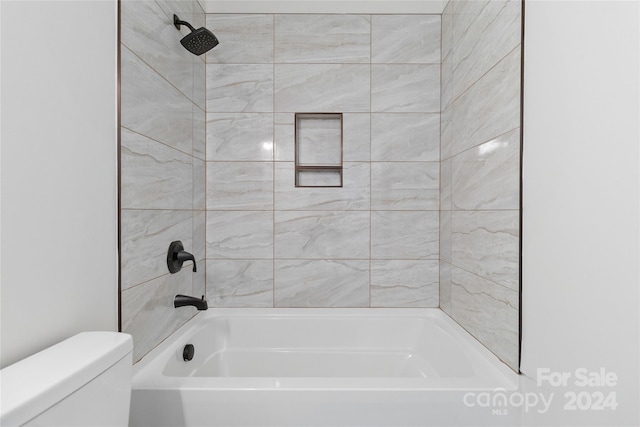 bathroom featuring tiled shower / bath combo and toilet