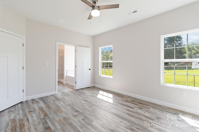 unfurnished bedroom featuring ceiling fan, ensuite bathroom, and light wood-type flooring