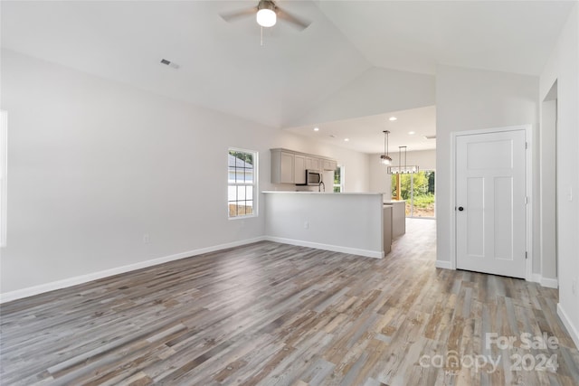 unfurnished living room with light wood-type flooring, ceiling fan, and high vaulted ceiling