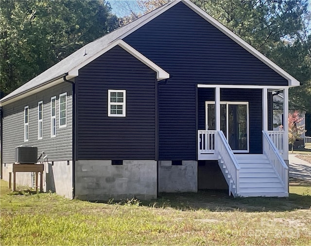 back of property with central AC unit and a lawn