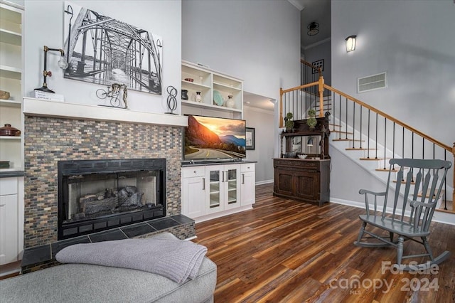 living room with a high ceiling, a tile fireplace, and dark hardwood / wood-style flooring