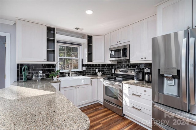 kitchen featuring light stone countertops, appliances with stainless steel finishes, white cabinetry, dark hardwood / wood-style flooring, and tasteful backsplash