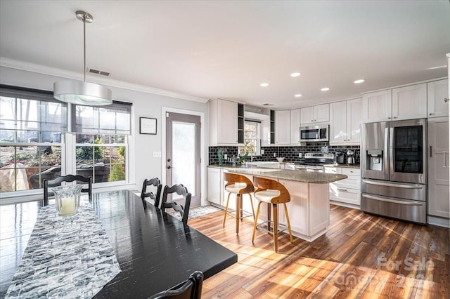 kitchen with crown molding, pendant lighting, appliances with stainless steel finishes, white cabinets, and light stone counters