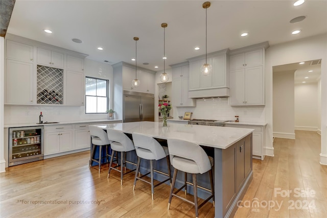kitchen with light wood-type flooring, stainless steel built in refrigerator, a kitchen island, and wine cooler