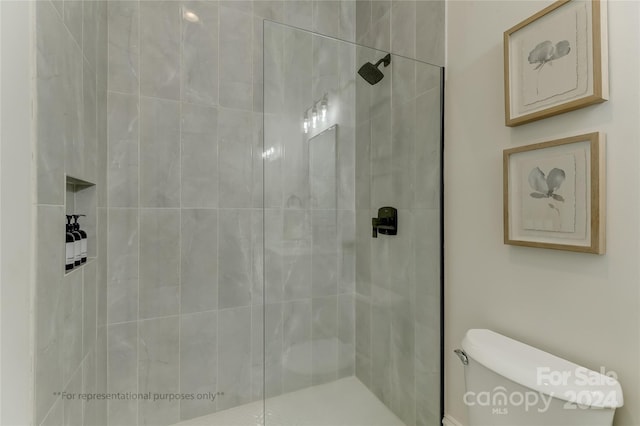 bathroom featuring a shower with shower door and toilet