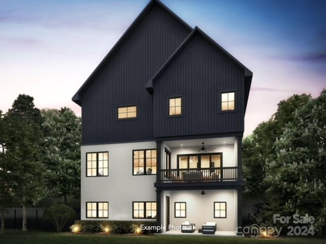 back house at dusk featuring ceiling fan and a balcony