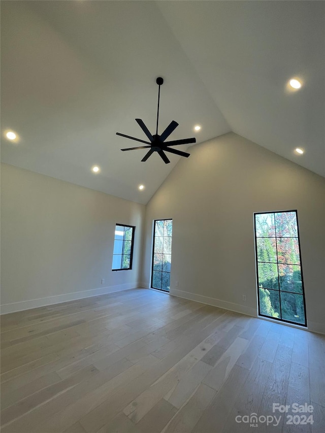 unfurnished room with ceiling fan, light wood-type flooring, and high vaulted ceiling