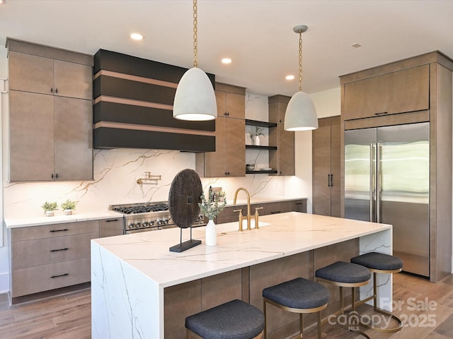 kitchen featuring pendant lighting, decorative backsplash, light hardwood / wood-style flooring, and premium appliances