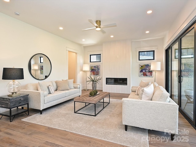 living room featuring ceiling fan, a fireplace, and light hardwood / wood-style floors