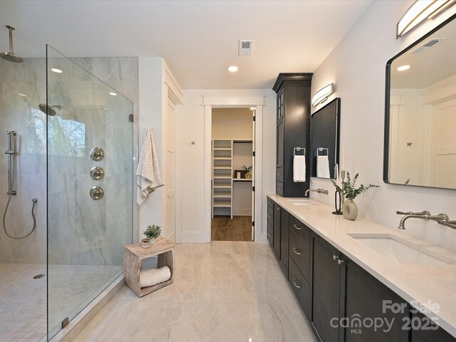 bathroom with tiled shower and vanity