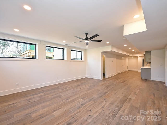 unfurnished living room featuring ceiling fan, wood-type flooring, and sink