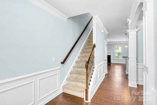 stairs featuring wood-type flooring and ornamental molding