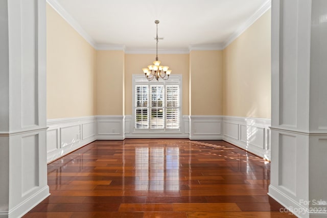 spare room with a chandelier, ornamental molding, and dark hardwood / wood-style floors