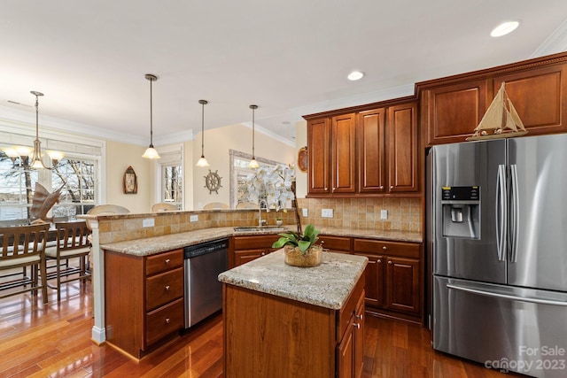 kitchen featuring decorative light fixtures, kitchen peninsula, appliances with stainless steel finishes, dark hardwood / wood-style floors, and an inviting chandelier