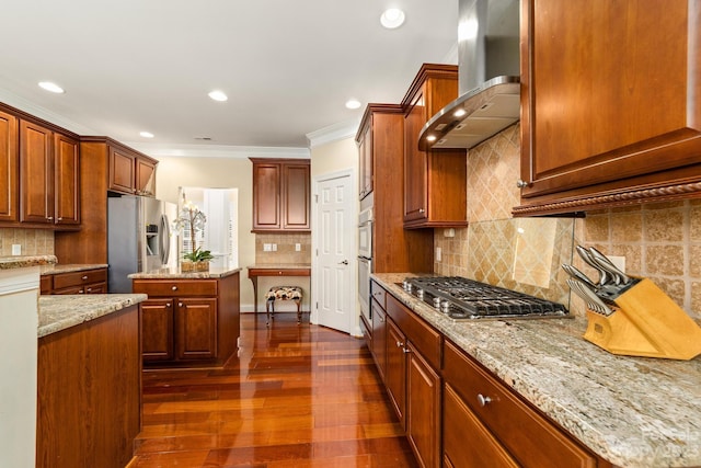 kitchen with dark wood-type flooring, appliances with stainless steel finishes, tasteful backsplash, light stone countertops, and wall chimney range hood