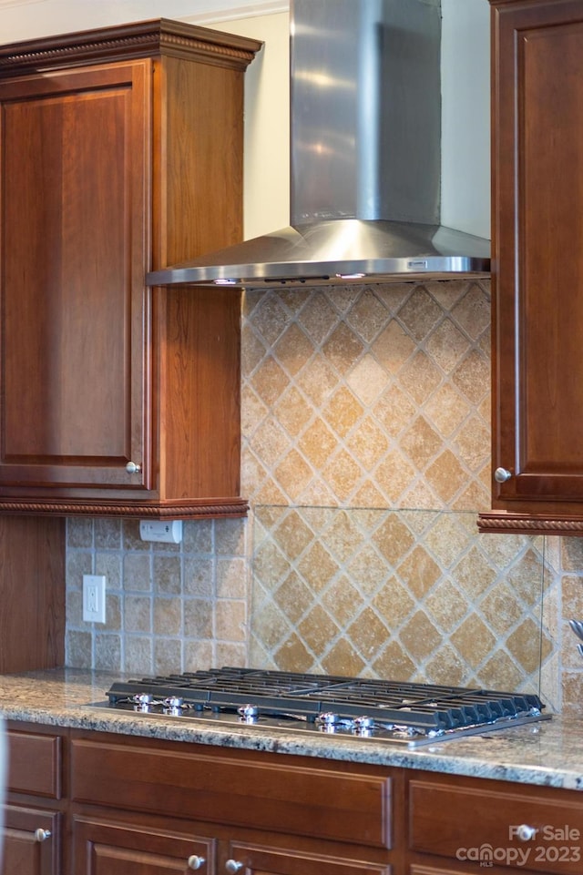 kitchen featuring wall chimney range hood, stainless steel gas stovetop, tasteful backsplash, and light stone countertops