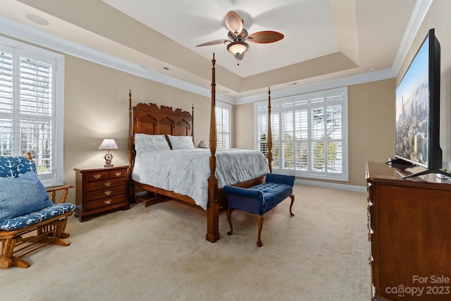 bedroom featuring a raised ceiling, crown molding, ceiling fan, and light carpet