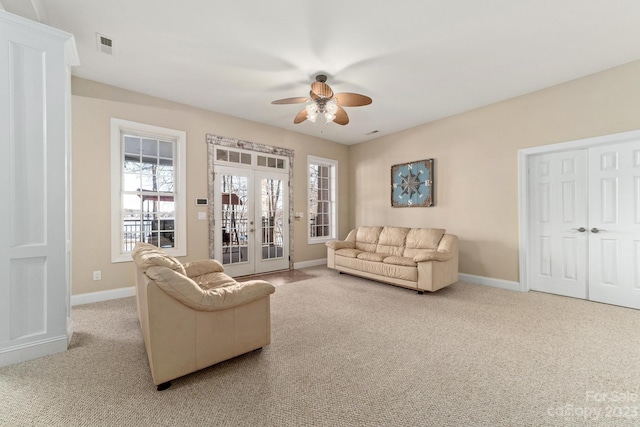 carpeted living room with ceiling fan and french doors