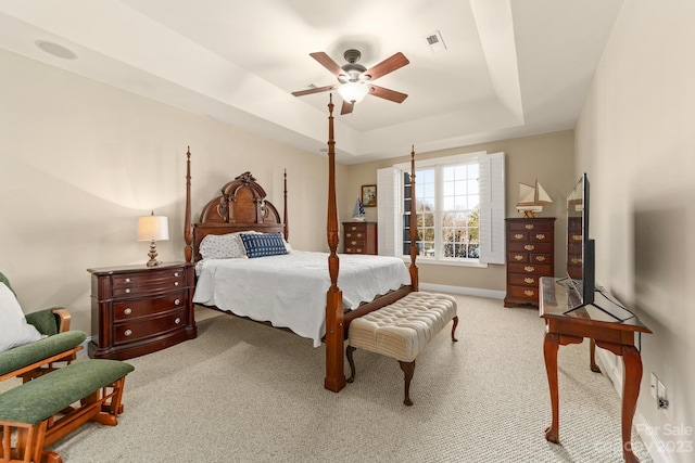 carpeted bedroom featuring a tray ceiling and ceiling fan