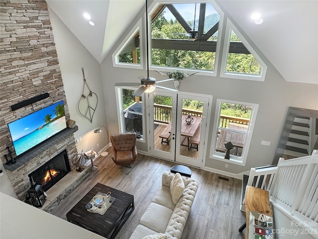 living room featuring ceiling fan, a fireplace, high vaulted ceiling, and wood-type flooring