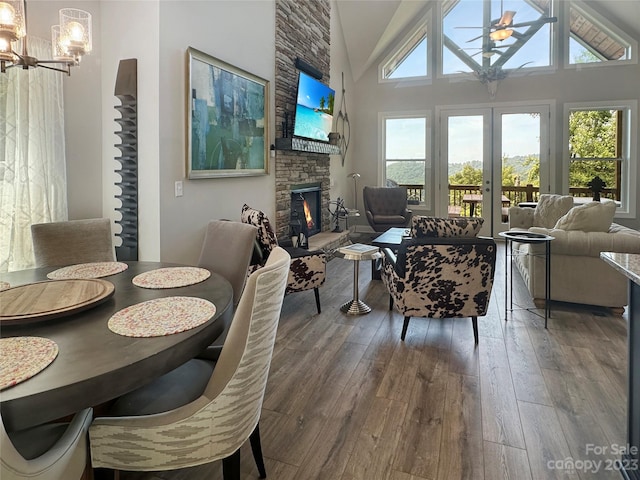 dining room with plenty of natural light, a stone fireplace, dark hardwood / wood-style floors, and a towering ceiling