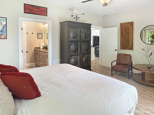 bedroom featuring ensuite bath, ceiling fan, black fridge, and hardwood / wood-style flooring