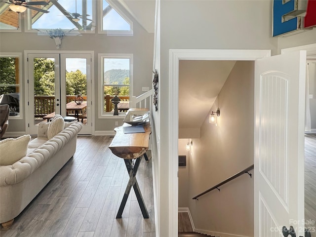 interior space featuring ceiling fan, light wood-type flooring, a towering ceiling, and french doors