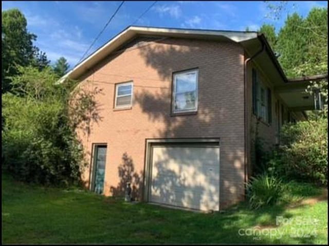 rear view of house featuring a garage and a yard