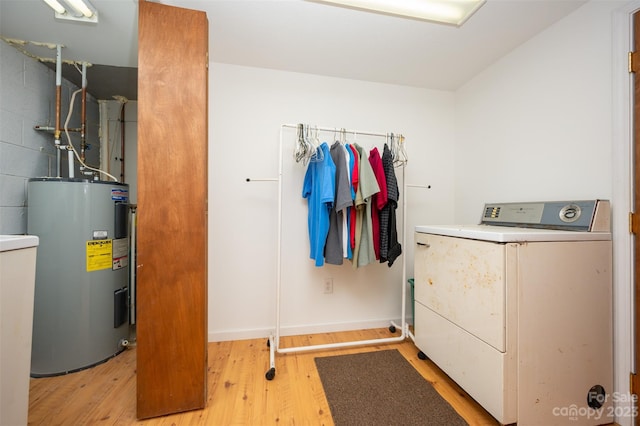 laundry area featuring electric water heater, light hardwood / wood-style floors, and washer / clothes dryer