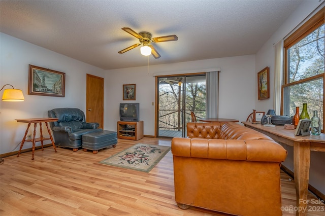 living room featuring a textured ceiling, ceiling fan, and light hardwood / wood-style flooring