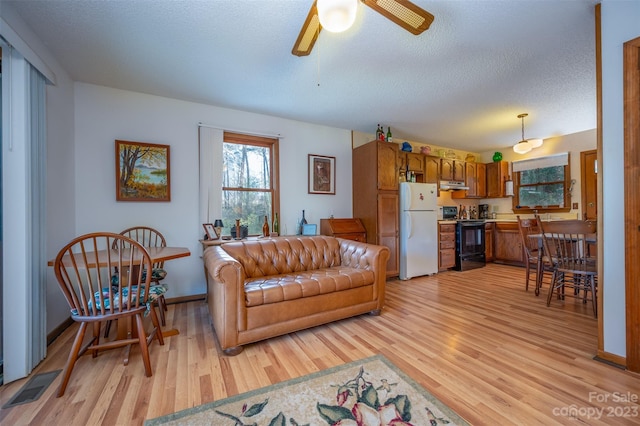 living room featuring light hardwood / wood-style floors, a textured ceiling, and ceiling fan