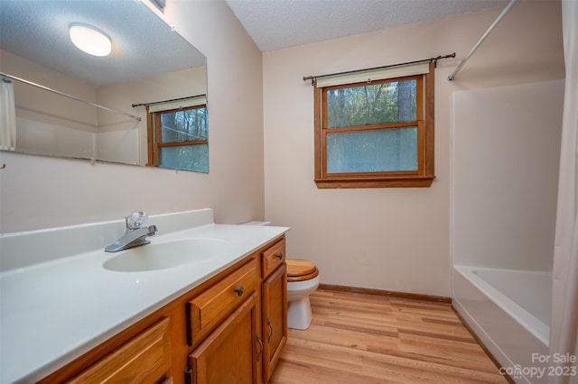 full bathroom featuring hardwood / wood-style floors, washtub / shower combination, a textured ceiling, toilet, and vanity