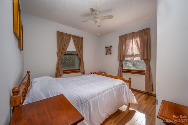 bedroom with ceiling fan, light hardwood / wood-style floors, and a textured ceiling