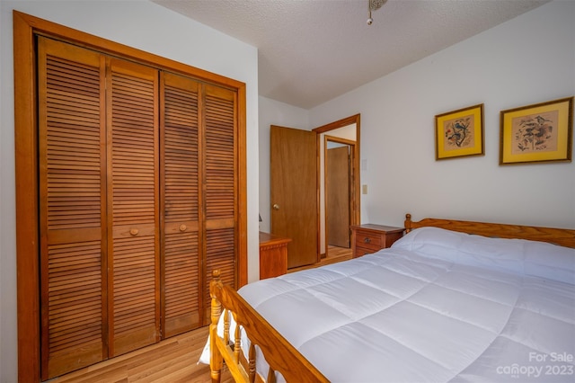 bedroom featuring a closet, a textured ceiling, and light hardwood / wood-style flooring