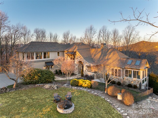 view of front of home with a fire pit and a front lawn