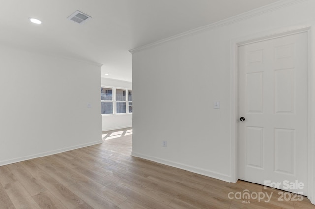 spare room with crown molding and light wood-type flooring