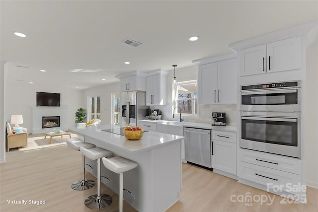 kitchen with white cabinetry, appliances with stainless steel finishes, sink, and pendant lighting