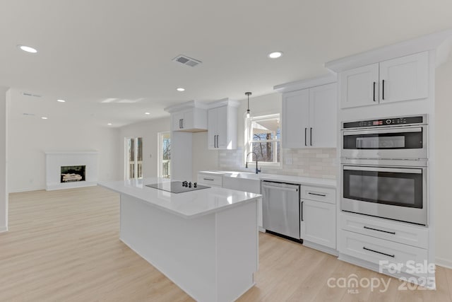 kitchen with white cabinetry, appliances with stainless steel finishes, a center island, and pendant lighting