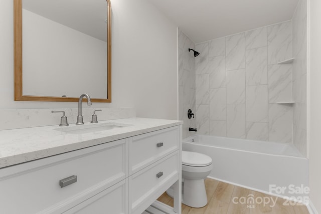 full bathroom with tiled shower / bath combo, vanity, wood-type flooring, and toilet