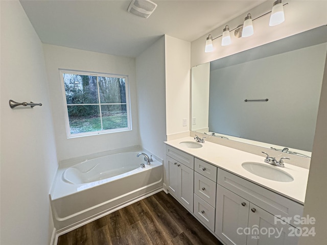 bathroom with hardwood / wood-style flooring, double vanity, and a bath