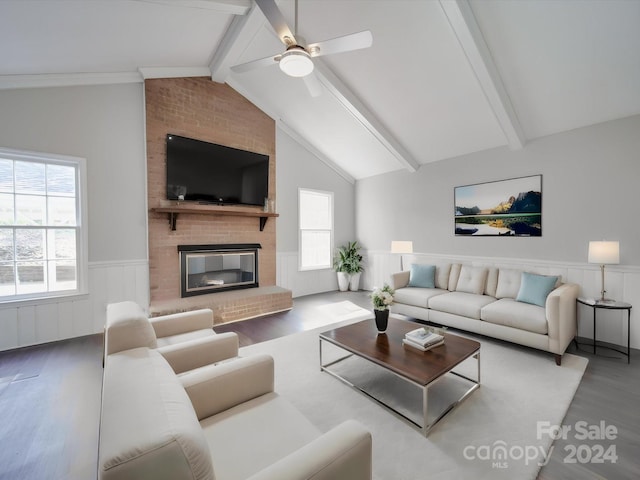 living room with ceiling fan, vaulted ceiling with beams, dark wood-type flooring, and a fireplace