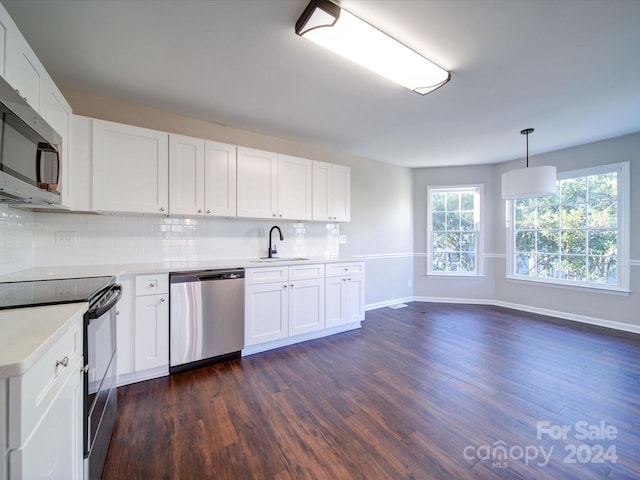 kitchen with dark wood-type flooring, appliances with stainless steel finishes, tasteful backsplash, sink, and hanging light fixtures