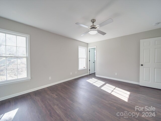 spare room with dark hardwood / wood-style flooring, ceiling fan, and a healthy amount of sunlight