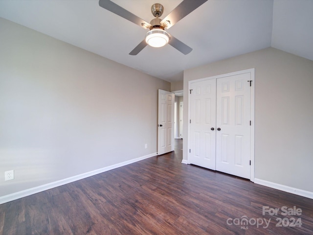 unfurnished bedroom featuring a closet, dark wood-type flooring, ceiling fan, and vaulted ceiling